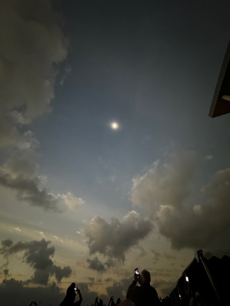 Image showing the sun in a clear patch of sky surrounded by clouds.